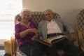 Front view of senior couple with photo album looking at camera in home Royalty Free Stock Photo