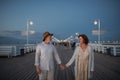 Front view of happy senior couple walking outdoors on pier by sea at dusk, holding hands. Royalty Free Stock Photo