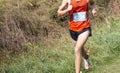 Runner running a race on a grass field downhill