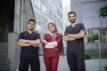 Three young confident multiethnic doctors, standing outside the hospital and looking at camera Royalty Free Stock Photo