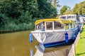 Holiday cruisers and pleasure craft moored up on a quiet river in the Norfolk Broads Royalty Free Stock Photo