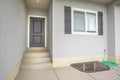 Front view of a home with gray front door and wood shutters on the window