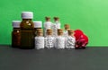 Front view of homeopath medicine bottles with flower buds and heart on green and dark background Royalty Free Stock Photo