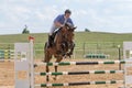 Front view of horseman in blue jumping on a horse