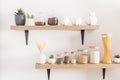 front view of the kitchen shelves with various eco-jars for storing bulk products. front view. white wall. cactus in