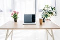 front view of laptop with blank screen, coffee cup, flowers and stationery Royalty Free Stock Photo