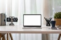 Front view laptop computer with blank display, books, coffee cup, stationery and potted plant on white table Royalty Free Stock Photo