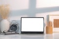 Front view laptop computer with blank screen, picture frame, alarm clock, notebook and pencil holder on white table Royalty Free Stock Photo