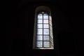 Front view of light through a Gothic stone church window among the dark background Royalty Free Stock Photo