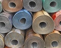 Front view on linoleum rolls with different color, texture, pattern stacked one on another,