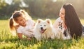 Front view of little girl, woman and cute dog that laying down on the grass outdoors Royalty Free Stock Photo