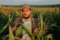 Front view looking at camera a serious tired young farmer male stands in a cornfield.