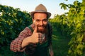 Front view looking at camera young winemaker male vineyard worker laugh thump up one hand happy.