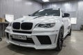 Front view of luxury very expensive new white BMW X6 M Lumma CLR tuning car stands in the washing box waiting for repair in auto