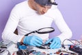 Front view of man showing process of mobile phone repair, radioman using tool equipment to change damaged part of smartphone. Royalty Free Stock Photo