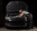 Front view of a mechanic repairing a black car