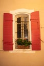 Barred window, with a planter and a pair of wood, red, shutters