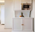 Front view of mini kitchen cupboard module cabinet with microwave and fruits plate. Classic style interior of white room