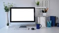 Mock up computer with blank screen and office supplies on white table at stylish work place. Royalty Free Stock Photo