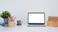 Mock up computer laptop with blank screen, house plant, pencils holder and boxes on white table. Royalty Free Stock Photo