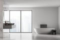 Front view of modern bathroom with double sink and white bathtub, large panoramic window, city view, minimalistic marble and Royalty Free Stock Photo