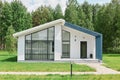 Front view of modern designed residential house with big windows, green lawn near building near the forest, real estate Royalty Free Stock Photo