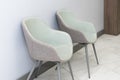 Front view of modern, simple chairs against grey wall in a minimal style, waiting room interior. Chairs in waiting room of doctor