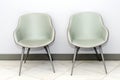 Front view of modern simple chairs against grey wall in a minimal style waiting room interior. Chairs in waiting room of doctor