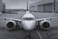 Front view of a modern twinjet airliner sitting on the concrete tarmac with lane markings in a large airport. Black and Royalty Free Stock Photo