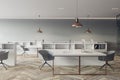 Front view on modern white work table with computers in spacious coworking office with grey chairs, light cabinet on light grey