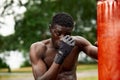 Front view of muscular black boxer punching towards camera with a deep and intense face outdoor. Boxing and Training Royalty Free Stock Photo