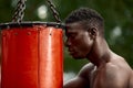 Front view of muscular black boxer punching towards camera with a deep and intense face outdoor. Boxing and Training Royalty Free Stock Photo