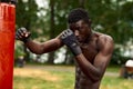 Front view of muscular black boxer punching towards camera with a deep and intense face outdoor. Boxing and Training Royalty Free Stock Photo