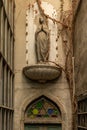 Front view of narrow alley entrance of ancient church with stone woman statue on wooden door Royalty Free Stock Photo