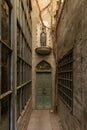 Front view of narrow alley entrance of ancient church with wooden door and stone woman statue