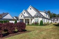 The front side view of a cottage craftsman style white house with a triple pitched roof with a sidewalk, landscaping and Royalty Free Stock Photo