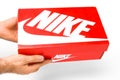 Front view on Nike box in mans hands on a white background. Close up mans hands holding a red box for shoes, San Francisco, USA,