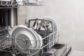 Open dishwasher with clean utensil inside, cutlery, glasses, dishes at kitchen Royalty Free Stock Photo