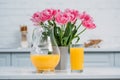 Front view of orange juice and vase with pink tulips on table Royalty Free Stock Photo