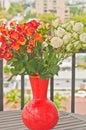 Vase filled with long stemmed orange and red colored baby roses Royalty Free Stock Photo