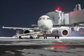 Front view of the passenger aircraft stands at the jetway on night airport apron. The baggage compartment of the airplane is open Royalty Free Stock Photo