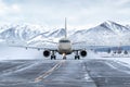 Front view of the passenger airplane taxiing on taxiway on the background of high picturesque mountains