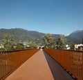 Front view of the pedestrian and bicycle path of a modern rusty bridge, with the Swiss Alps in Ticino in the background. Strong