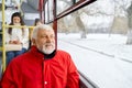 Elderly bearded man looking at window while travelling in public transport.