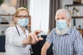 Front view of pleasant likable blond woman doctor, in face mask, holding a syringe with vaccine or medicine, ready to Royalty Free Stock Photo