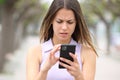 Worried teen checking smart phone content in the street