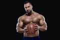 Front view portrait of an attractive sportsman holding a basketball with both hands isolated on black background Royalty Free Stock Photo