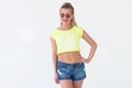 Front view portrait of beautiful model posing in a trendy summer outfit, wearing bright yellow t-shirt, sunglasses Royalty Free Stock Photo