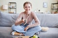 Carefree woman sitting on sofa holding remote control looking at camera Royalty Free Stock Photo