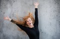 Portrait of cheerful young woman with red hair standing against gray background. Royalty Free Stock Photo